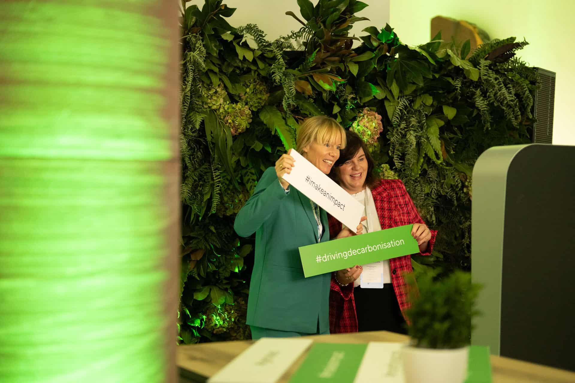 Zwei freudige Damenposiert mit Schildern vor interaktiven Fotobox von formwandler events